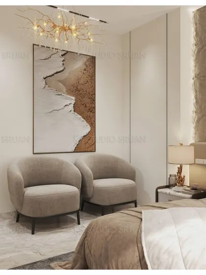 A cozy seating corner in the bedroom, with two comfortable armchairs and a piece of art depicting a serene beach scene, enhancing the room's tranquil vibe.