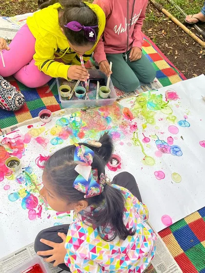 Children engaged in bubble painting at one of our outdoor workshops. This unique process art technique involves blowing colored bubbles onto paper to create beautiful, unpredictable patterns.