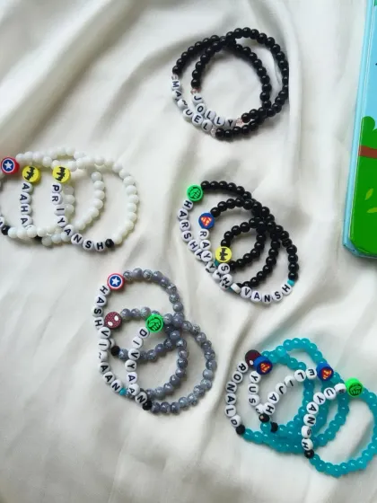 A flat lay of our boys' name bracelets, showing different color combinations and superhero charms like Captain America and Batman.