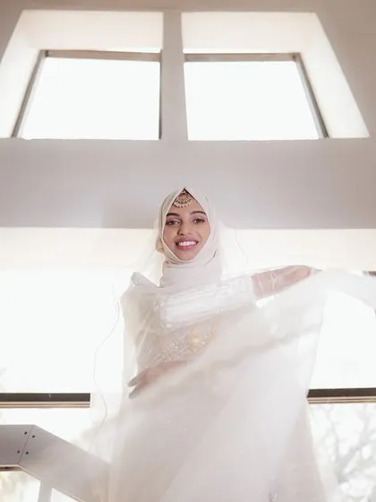 A joyful, low-angle shot of the bride, with light streaming in from the windows behind her, creating an angelic and happy portrait.