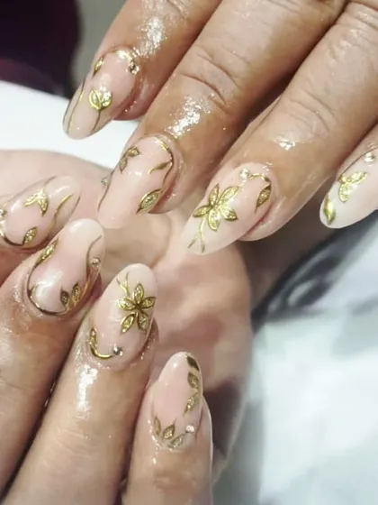 Golden hour for your nails. This elegant set features delicate, hand-painted gold foil flowers and leaves over a sheer nude base.