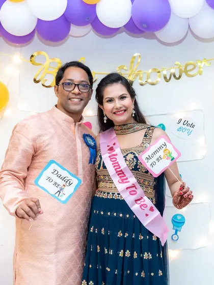 A fun portrait of the 'Daddy to Be' and 'Mommy to Be' with cute props at their baby shower. Our photography style is playful and real, capturing the fun side of your celebration.