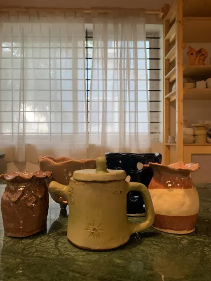 A delightful collection of hand-built pieces from one of our youngest students. This set includes a star-stamped teapot, a two-toned vase, and other imaginative creations, all fresh from the kiln.