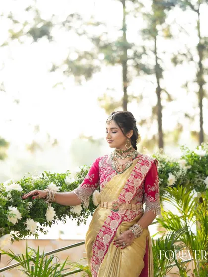 The sister of the bride in a serene outdoor setting. Her makeup is soft and traditional, perfect for a daytime Muhurtham ceremony.