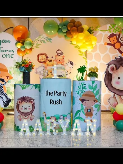 A full view of Aaryan's jungle-themed party, showcasing the complete setup with character cutouts, a custom backdrop, and a happy family enjoying the celebration.