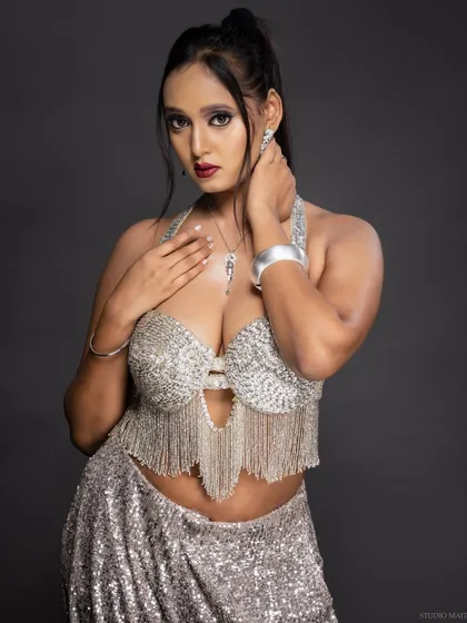 A glamorous portrait of a model in a silver fringed top and matching skirt.
