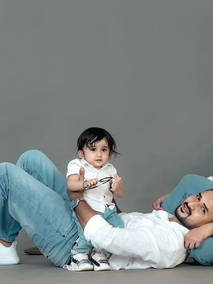 A relaxed and modern family pose. The casual arrangement on the studio floor allows for a portrait that feels both professionally shot and genuinely comfortable.