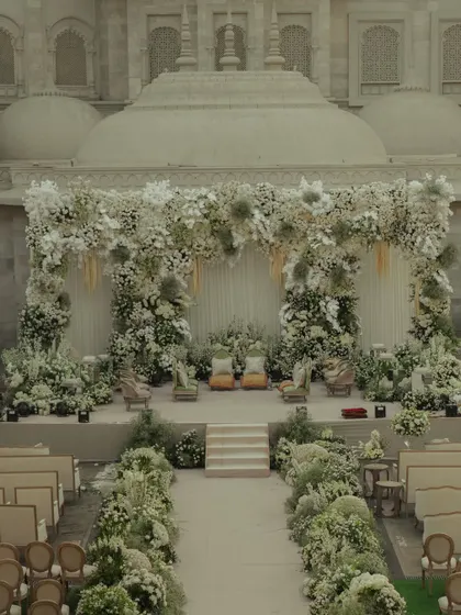A full view of the all-white mandap I designed at Fairmont Jaipur, showing the perfect symmetry of the floral arch and the aisle, creating a serene and majestic atmosphere.
