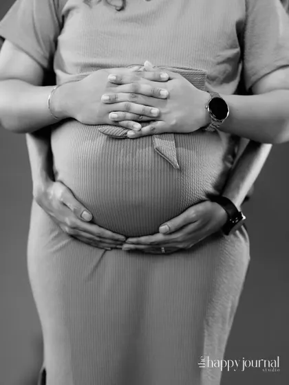 A black and white close-up focusing on the hands of the couple cradling the baby bump. This artistic shot symbolizes their shared love and protection for their unborn child.