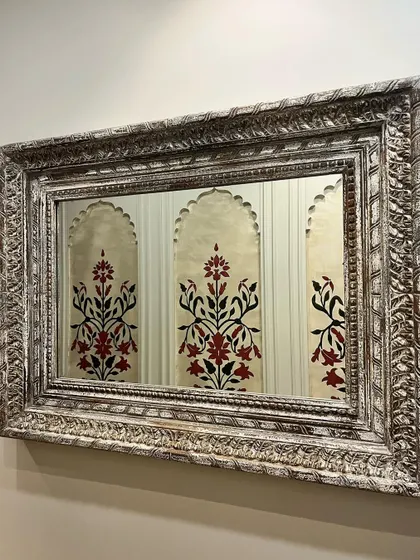A reflection in a mirror showing my hand-painted Mughal-style floral motifs. The ornate frame and the reflection create a beautiful, layered composition.