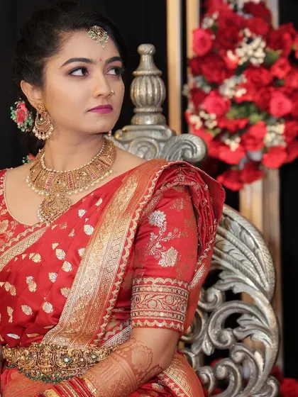 A regal bride in a red Sabyasachi saree. The makeup is kept classic and elegant to complement the grandeur of her outfit and the stunning backdrop.