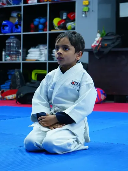 A young student kneels in the traditional seiza position, demonstrating the focus and discipline that is central to our karate training.