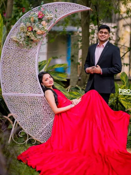A dreamy portrait with the bride-to-be lounging on a crescent moon prop. Her red gown cascades to the ground, creating a romantic and whimsical scene.
