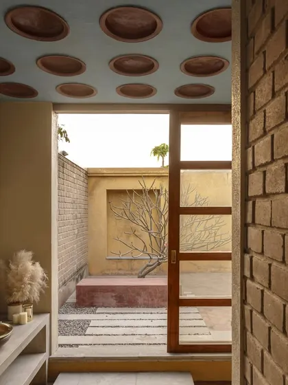This bathroom opens into a private courtyard, creating a unique indoor-outdoor experience. The ceiling features terracotta pot fillers, and the walls are made of stabilized earth blocks from the site.