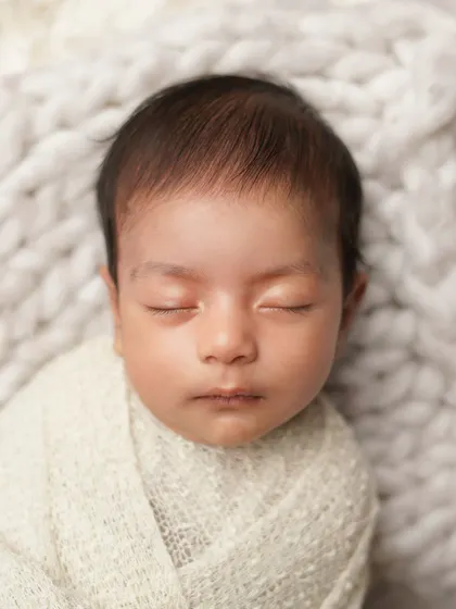 A simple, classic portrait of a sleeping newborn's face. The clean composition and soft lighting highlight the perfection of their features.
