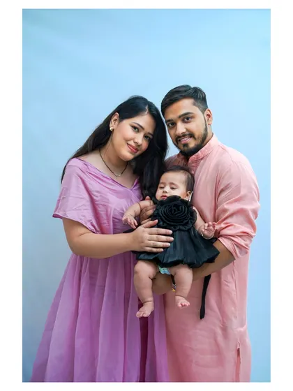 A lovely family portrait with parents and their baby girl, dressed in coordinating colors.