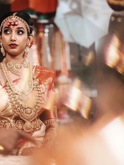 A beautiful candid portrait of a South Indian bride during her wedding ceremony. The soft focus and warm lighting highlight her attentive expression as she participates in the rituals.