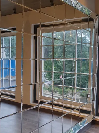 A mirror wall is a great way to create the illusion of space. This example shows how a beveled mirror grid can make a room feel larger and brighter.
