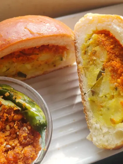 A perfect cross-section of the Baked Vada Pav, showing the generous potato filling and chutney inside the soft, golden-brown bun.