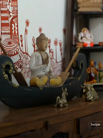 Duplicate of 175. A decorative corner featuring a Buddha statue in a boat, along with other small brass idols. These details infuse the space with spirituality and traditional craftsmanship.