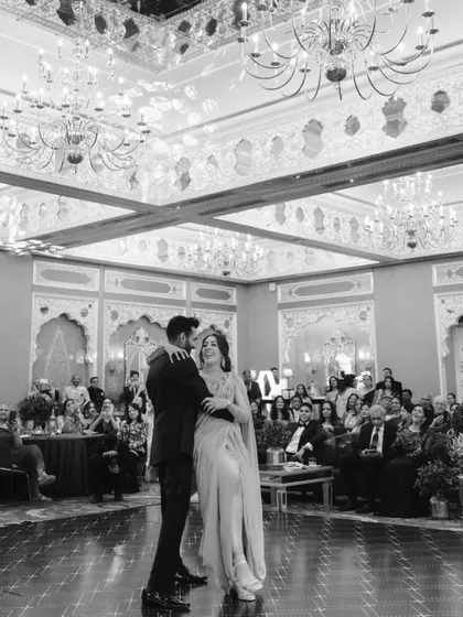 Sid and Kanika's first dance in a grand ballroom. This black and white photo focuses on their joy and the elegant setting of their reception.