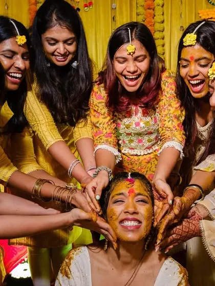 The bride surrounded by her smiling friends as they all apply haldi, a perfect picture of friendship and celebration.