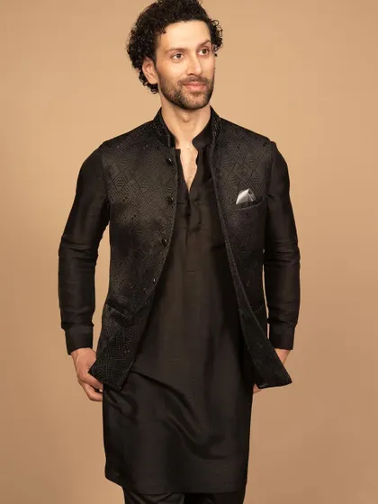 A luxurious black Nehru jacket with subtle, tonal embroidery, layered over a matching black kurta. This all-black look is the definition of sleek, modern elegance, perfect for an evening reception or cocktail event.
