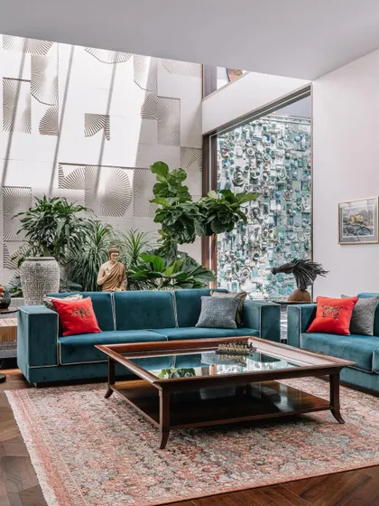 This living room is designed around a central courtyard, with views of the stunning ceramic and sandstone murals. The teal sofa with pops of red provides a comfortable and colorful place to relax and enjoy the home's unique architectural features.