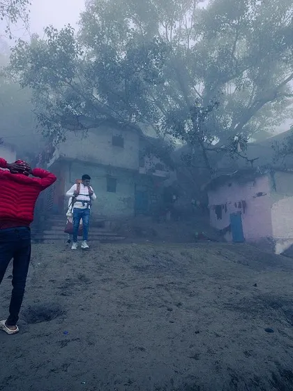 People on the Yamuna ghat during a foggy morning, their figures appearing as distant silhouettes in the mist.