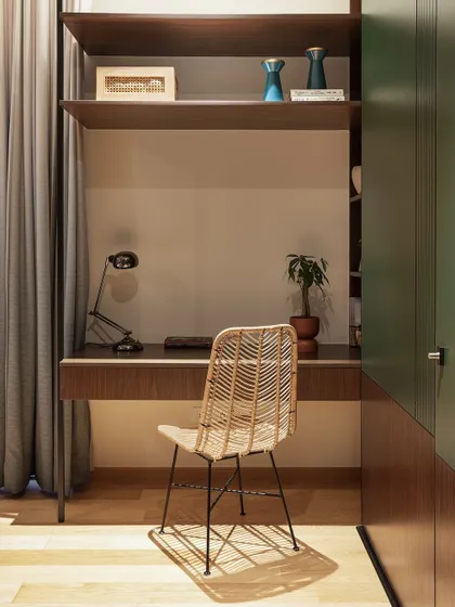 This compact study nook is cleverly built into a wardrobe unit. The dark wood desk and shelving, paired with a cane chair, create a cozy and efficient workspace.