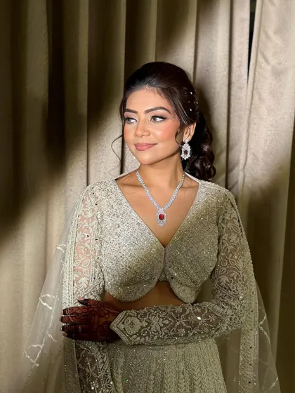 A three-quarter view showing how the makeup complements her elegant hairstyle and the single pop of color from her ruby necklace.