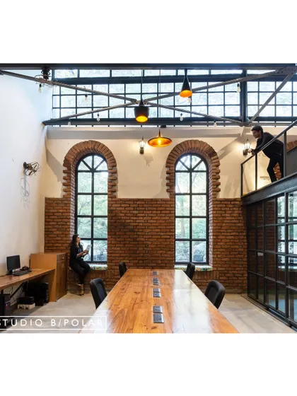 Inside the WhiteBalance Office, we preserved the industrial character with exposed brick and large arched windows. The long, custom-built pallet wood table sits in a double-height space, perfect for team meetings and collaborative work.