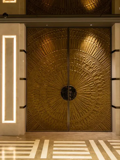 The ornate, custom-designed brass doors of the theater at Maison INOX. These doors are a work of art in themselves, reflecting the contemporary take on Art Deco that defines the entire space.