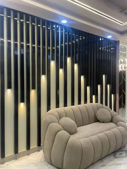 This plush, channel-tufted sofa is the star of the show. It is placed against a dramatic black and white slatted wall with integrated lighting, creating a very modern and high-impact seating area.