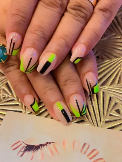 A bold, geometric design on coffin-shaped nails. The sheer nude base is decorated with sharp lines and color blocks in neon green and black.