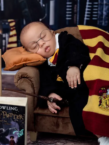 This little wizard is dreaming of casting spells. The focus here is on the baby, peacefully asleep with his wand and Gryffindor scarf.
