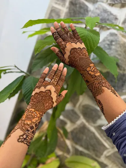 The same non-bridal design set against a natural green background, which makes the henna stain pop.