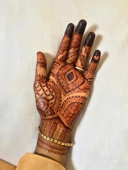 A slightly different angle of the same geometric palm design. Notice the small heart detail on the pinky finger, a popular modern touch in bridal mehndi.