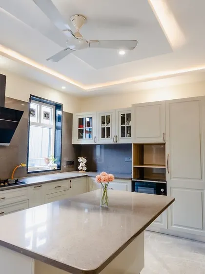This spacious island kitchen features pale green cabinets and a large central island, creating a clean and airy atmosphere.