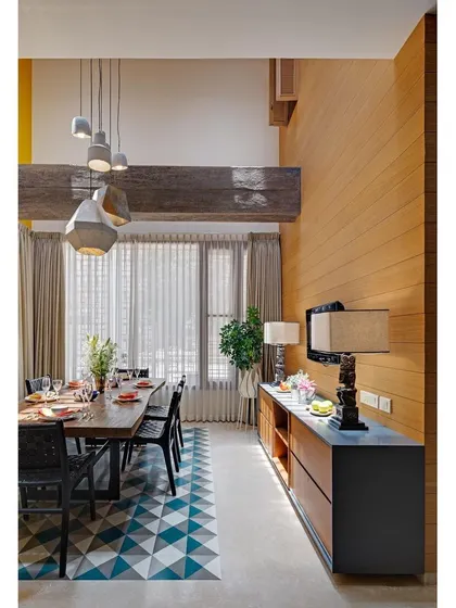 The dining area in Nataraj House, where a reclaimed wood beam and a tree-top dining table emphasize our commitment to using natural and repurposed materials.