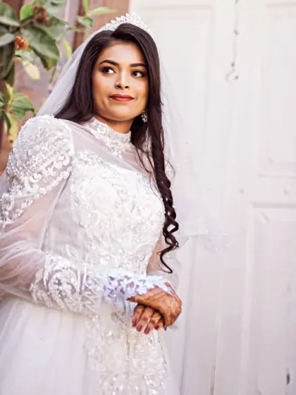 A beautiful portrait of our bride on her wedding day. This gown features a high neckline and intricate beading on the sleeves and bodice, creating a regal and elegant look.
