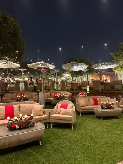 A wide shot of the lawn seating at night, showing the ambient lighting from patio heaters and string lights.