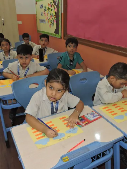 A classroom full of students is busy with a creative writing and drawing activity, each child focused on their own unique work.