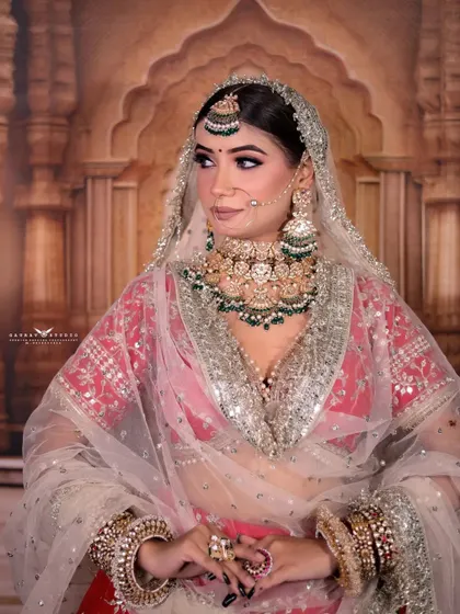 A medium shot of the bride, with her veil creating a beautiful frame around her. The focus is on her elegant posture and the grand scale of her bridal jewellery.