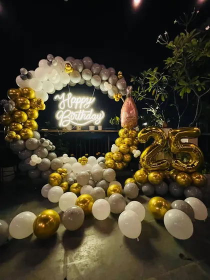 Another view of the elegant 25th birthday terrace setup, highlighting the full circular balloon arch and the "Happy Birthday" neon sign.