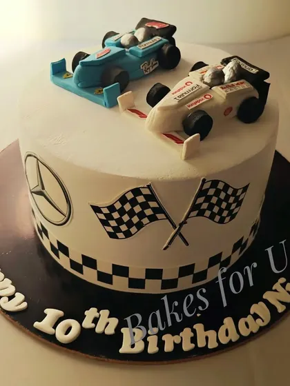 A Formula 1-themed cake with two handcrafted, edible race cars on top. The checkered flag design around the base completes the high-speed look.