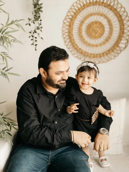 A father and daughter sharing a smile. The simple background keeps the focus on their relationship.