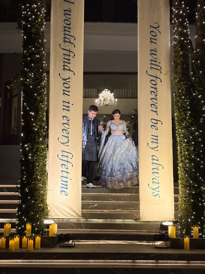 'I would find you in every lifetime.' These custom-printed banners, illuminated and flanked by fairy-light pillars, created a deeply romantic and personal entrance for the couple.