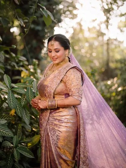 A beautiful portrait of the bride in her traditional South Indian saree, a moment captured in the lush greenery of the venue.