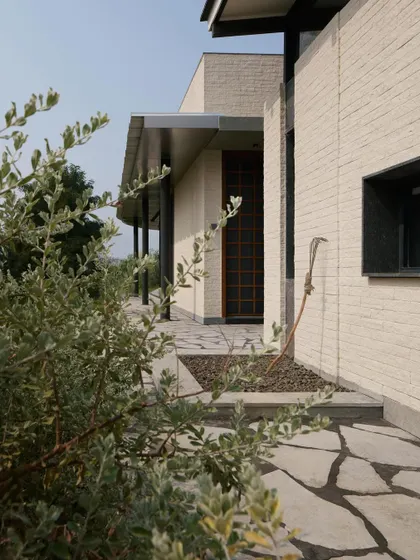 The entrance of Pavilion House, with its simple wooden door and textured white brick facade.